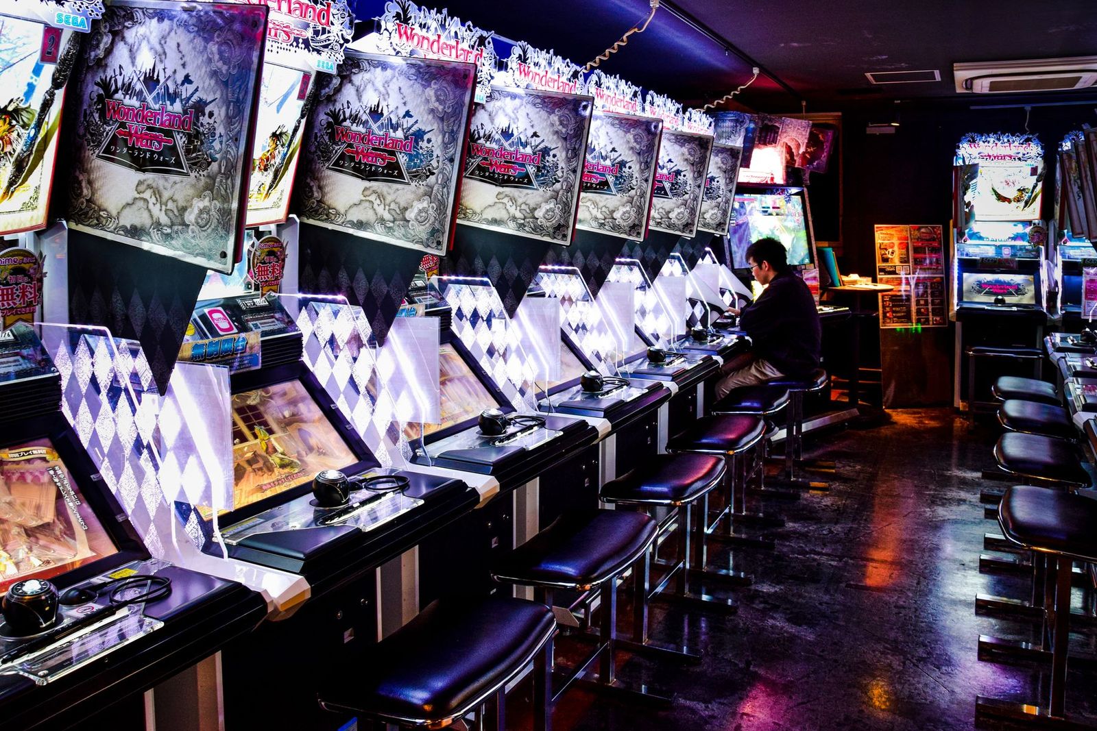 ネオンに照らされた東京のゲームセンターで遊ぶ男性